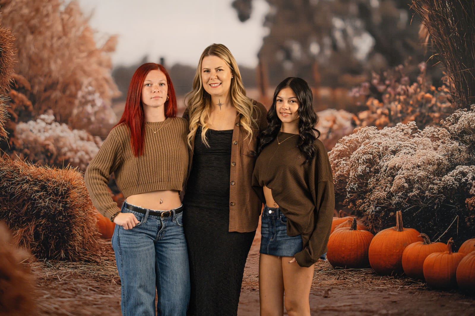Mother with her two daughters among the pumpkins and dried grasses.