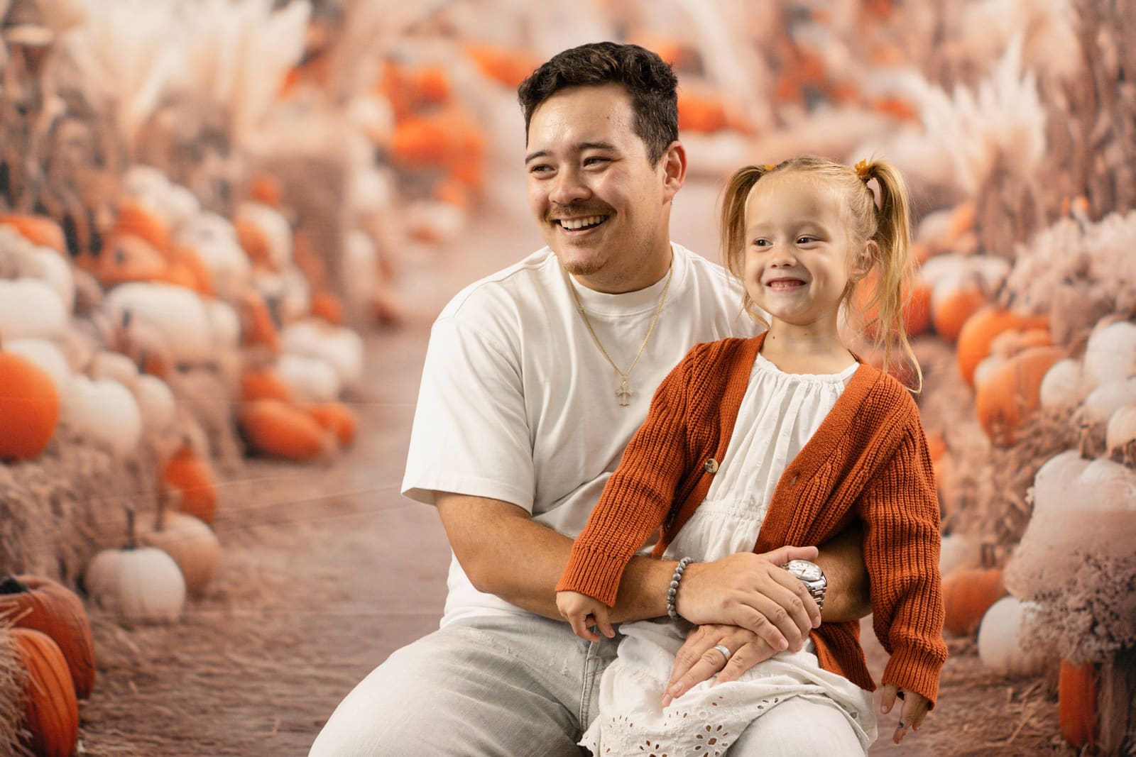 Father and his preschooler smiling together in the pumpkin patch mini set.