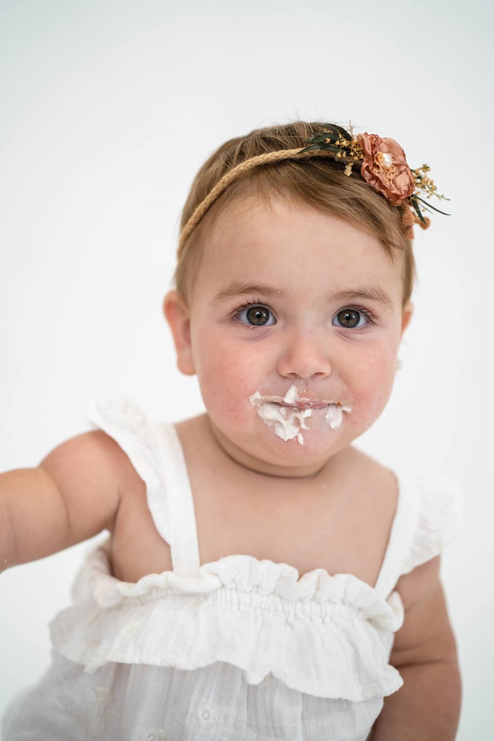 Child reaching for birthday cake during a Vacaville cake smash photography session.
